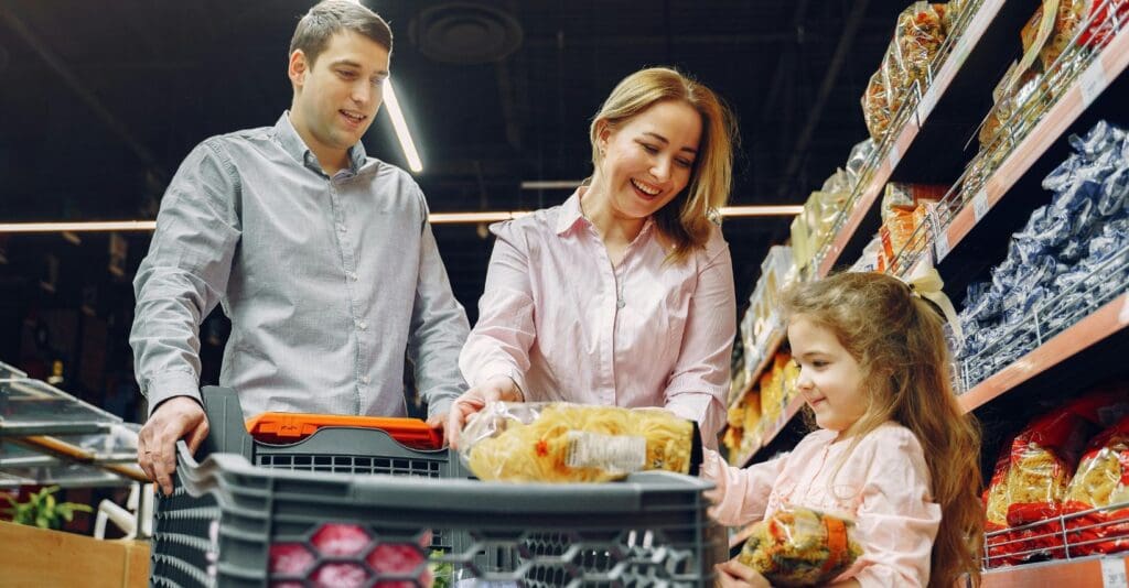 Famiglia che mette alimenti in un carrello della spesa